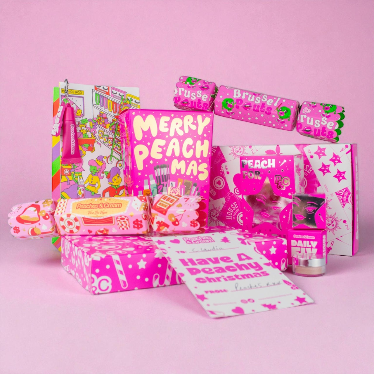 Peaches & Cream Peachmas Christmas gift sets displayed in pink festive packaging, including makeup products, crackers and stocking fillers.
