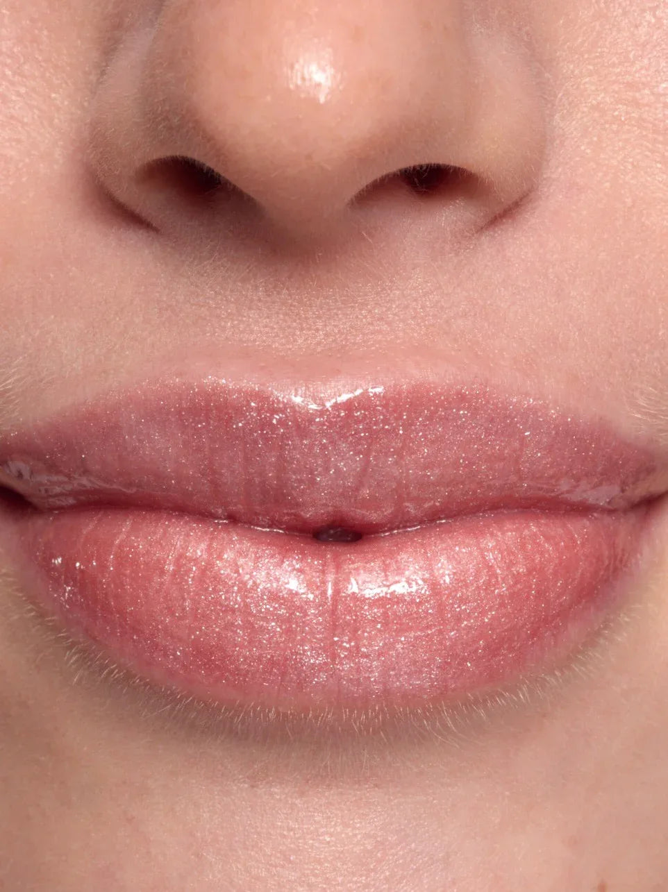 Close-up of a person's lips with Bubble Pink lip gloss tube by Peaches & Cream