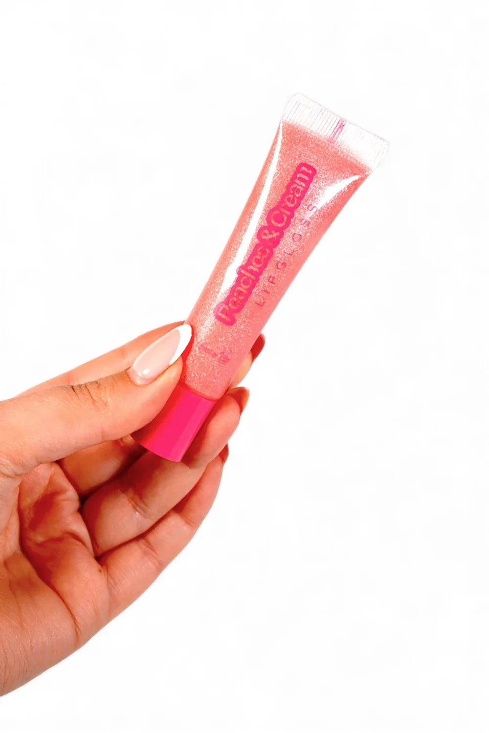 Bubble Pink lip gloss tube by Peaches & Cream held by a hand with a white background