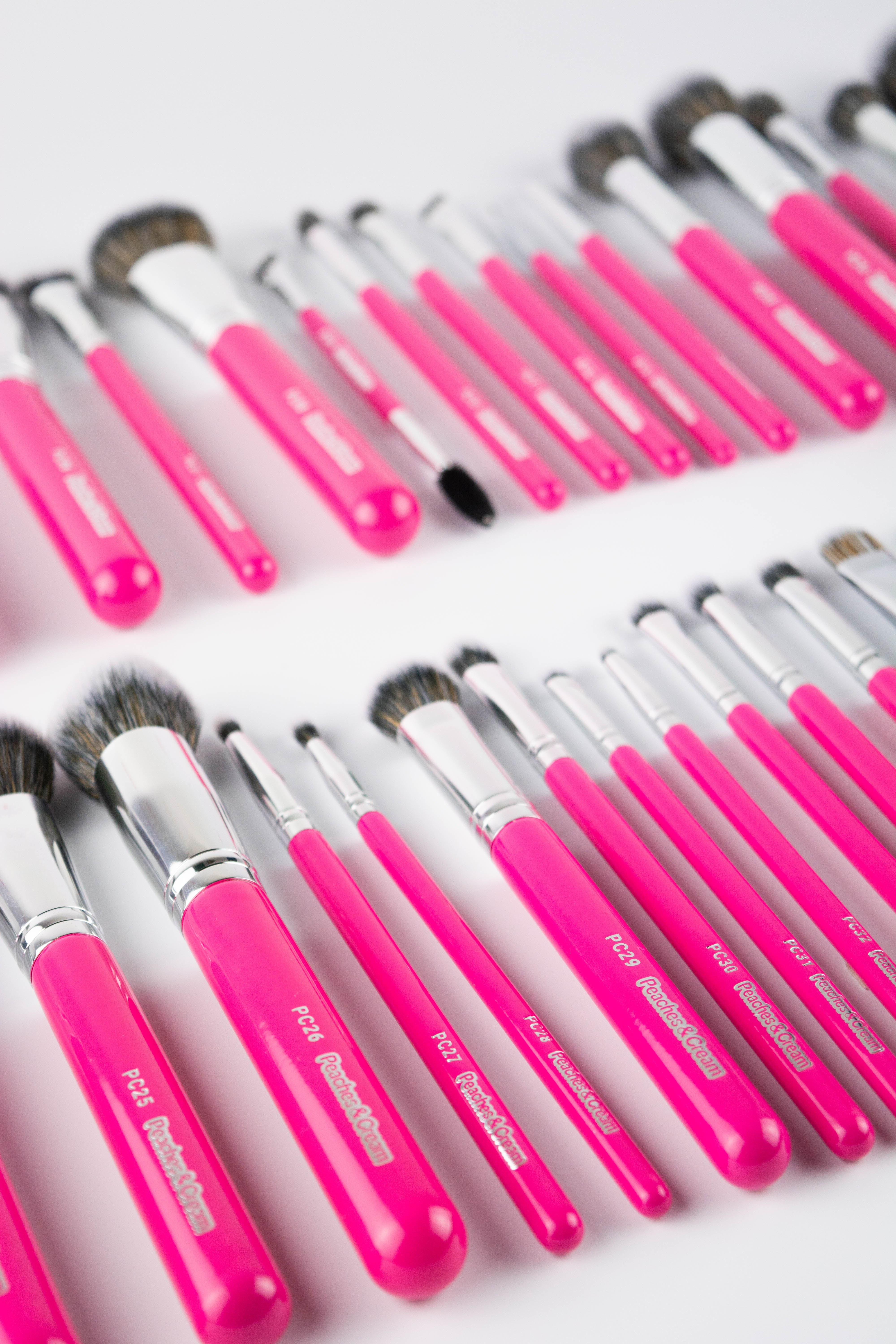 Set of pink makeup brushes with silver ferrules on a white background
