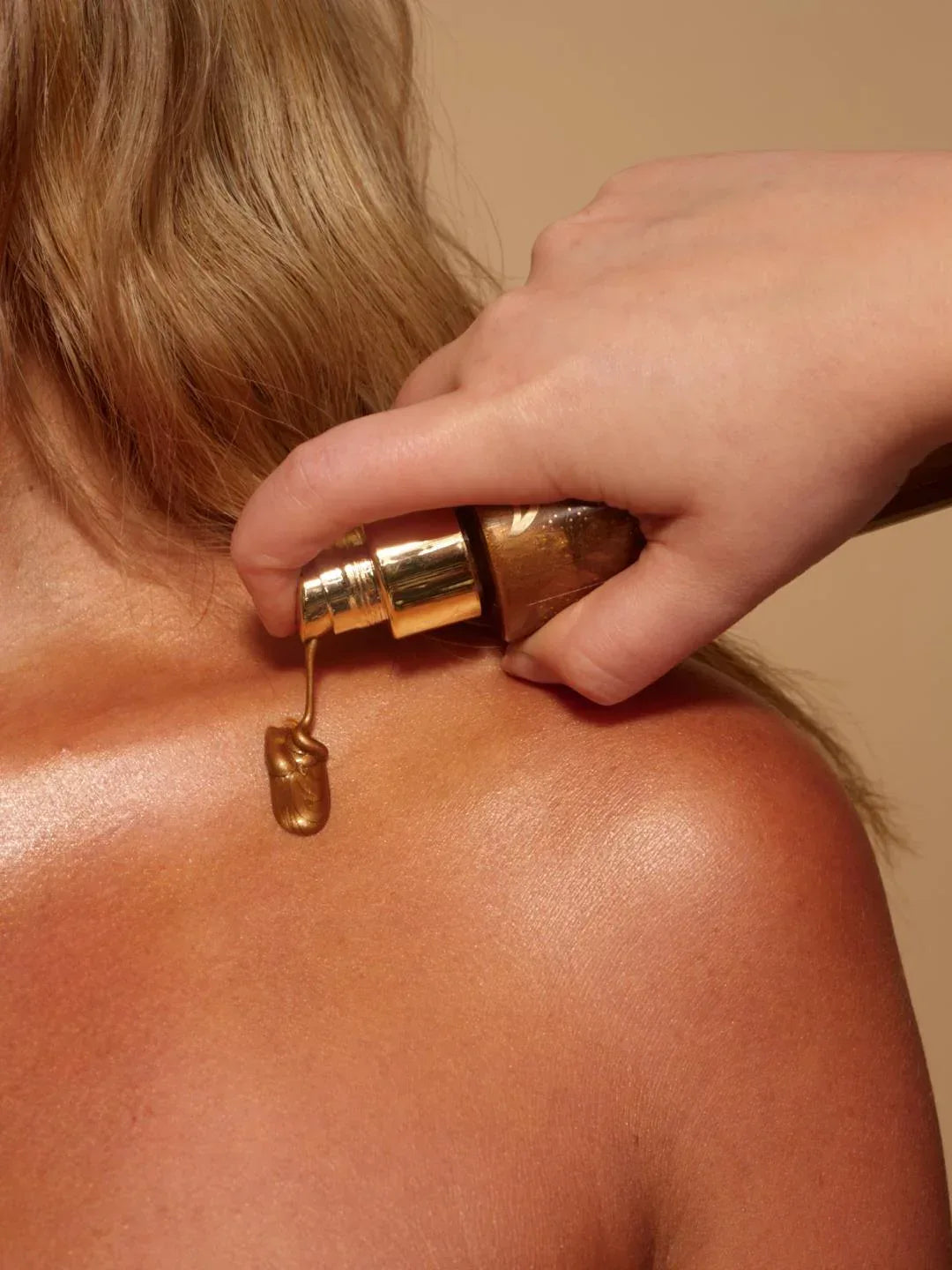 body glaze body shimmer by peaches and cream being dispensed across models shoulder